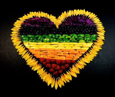 Picture of Heart made of rainbow stripes of food, with yellow flower petal border